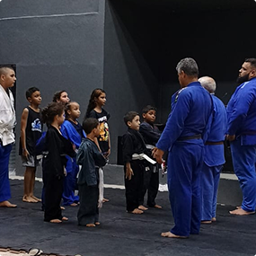 Turma de crianças em kimonos de jiu-jitsu com seus instrutores.